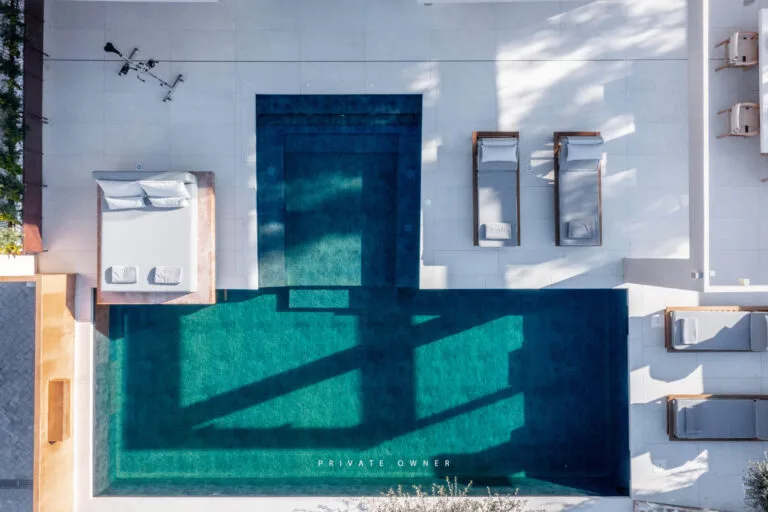 Drone photography from a villa for holiday rent in Greece showing a luxury swimming pool with sunbeds with nice aesthetics for the booking platforms